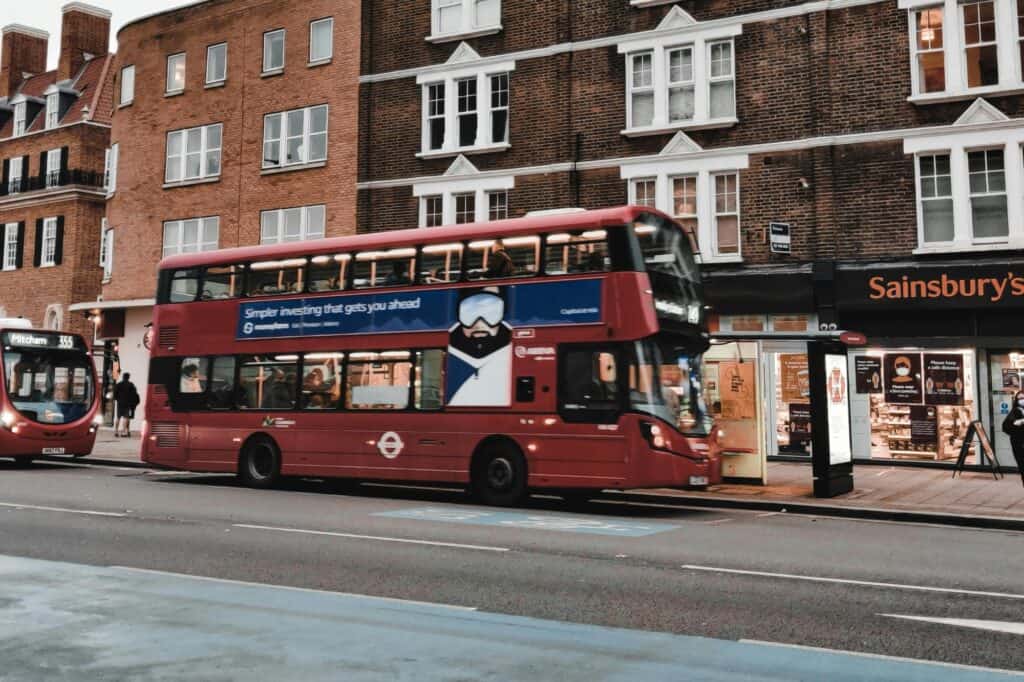 A red London bus is picking up passengers