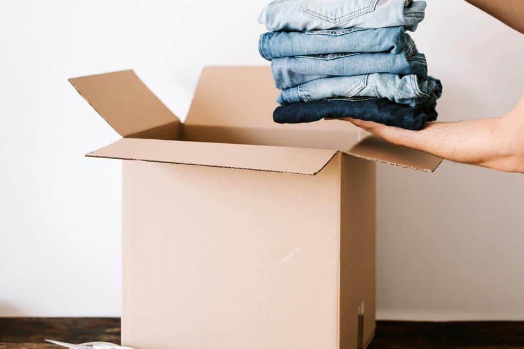 Pairs of jeans are being packed in a box in the concept of moving to Hendon.