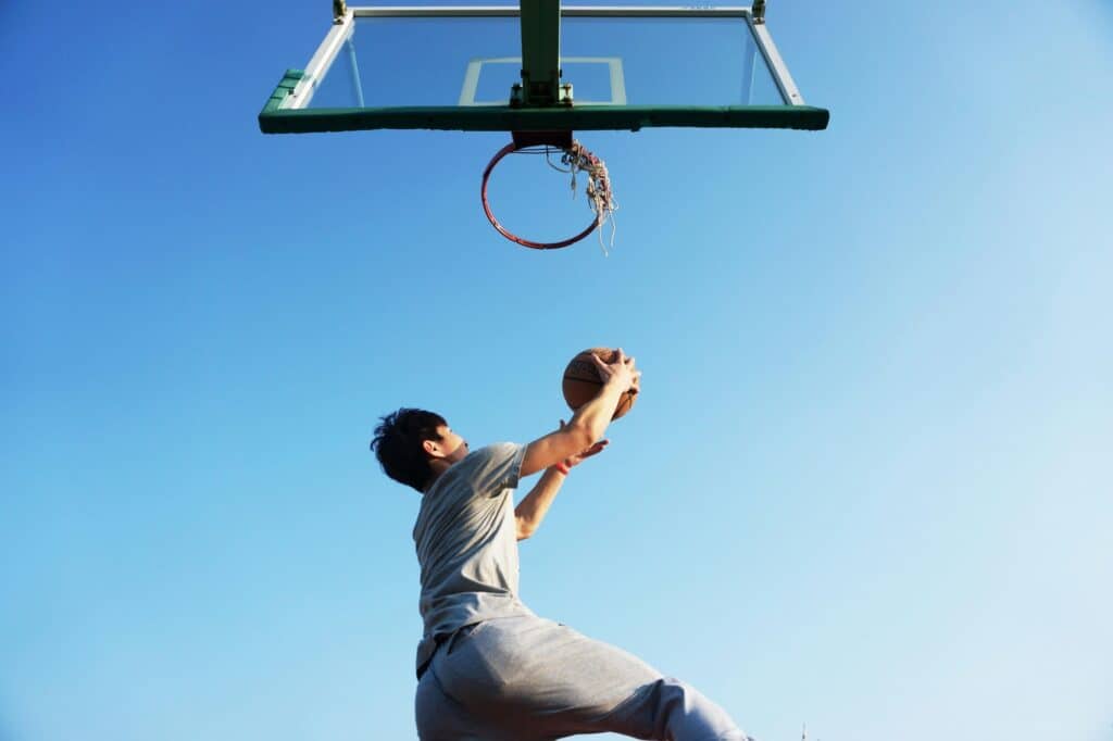 A male student is jumping to shoot a basketball