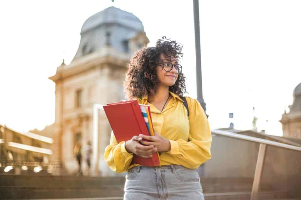 A female student is walking down a staircase while holding books