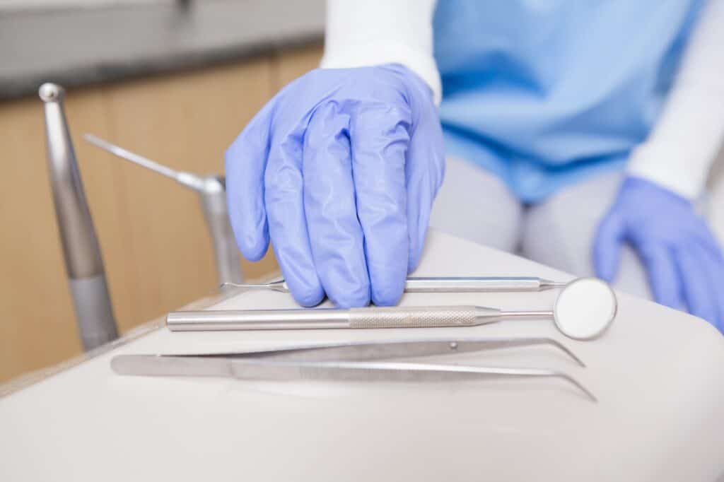 Cropped image of a dentist's hand picking a dental tool in the concept of 'top services and amenities in Hendon'.
