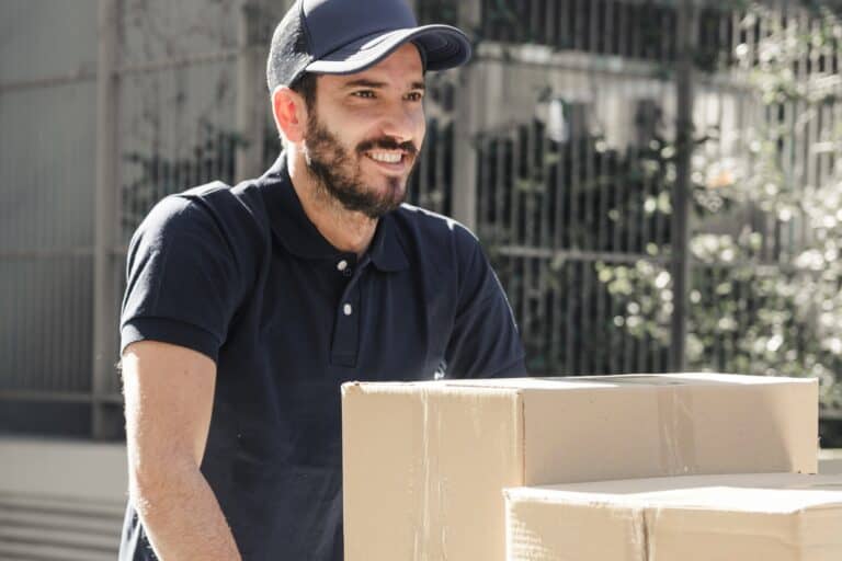 A smiling man and van pushing moving boxes on a cart in the concept of 'How to Ensure an Efficient Move with a Man and Van Service'.